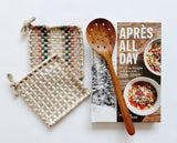 Apres all day cookbook paired with beautiful handwoven potholders and a teak strainer spoon.