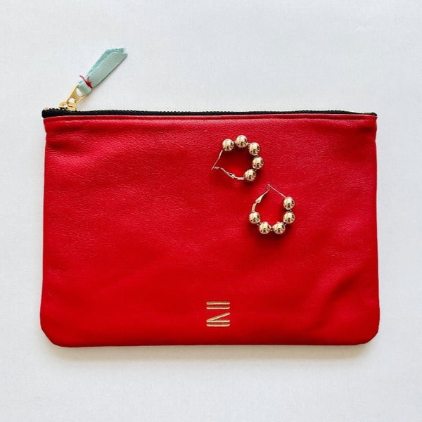 Red leather pouch from Certain Standard featured with Paloma earrings from Shashi.