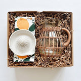 Hazelmade tea towel paired with a handmade ceramic juicer and rattan pitcher.