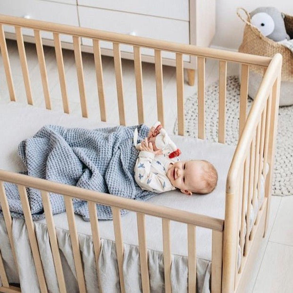 Baby in crib with waffle baby blanket.